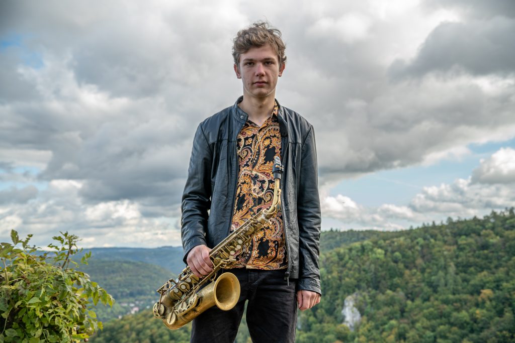 Jakob Manz mit Saxophon vor dem Panorama der schwäbischen Alb